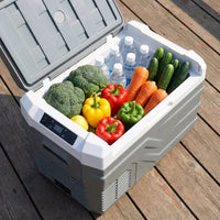 Glacière à compresseur ISKALDO Nomad 25 sur une terrasse, remplie de fruits et légumes frais